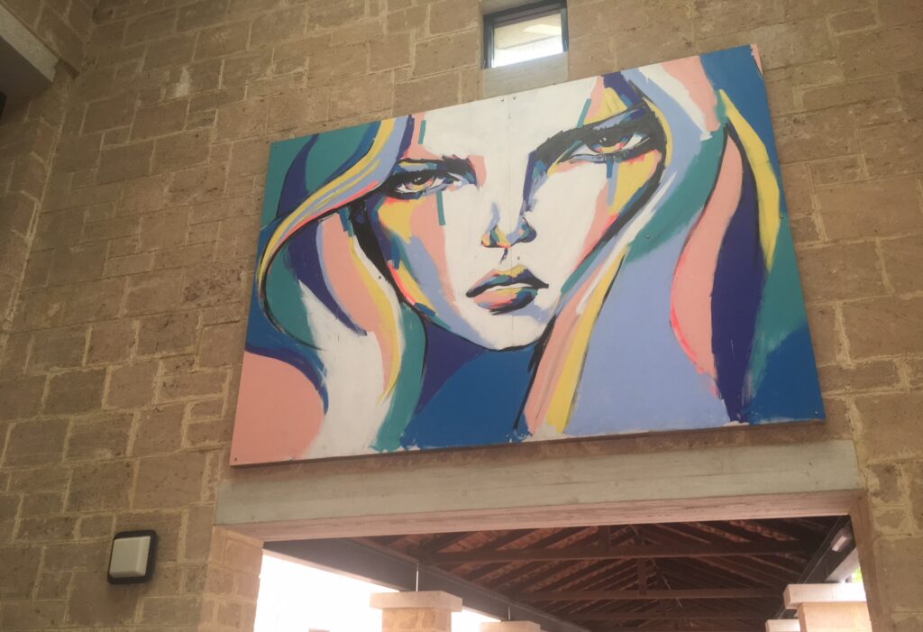 A vibrant mural of a woman's face with bold, colorful brushstrokes. Artwork: Untitled 1 (2015) by Anya Brock.