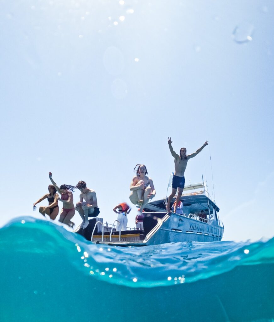 Kids jumping off boat on water